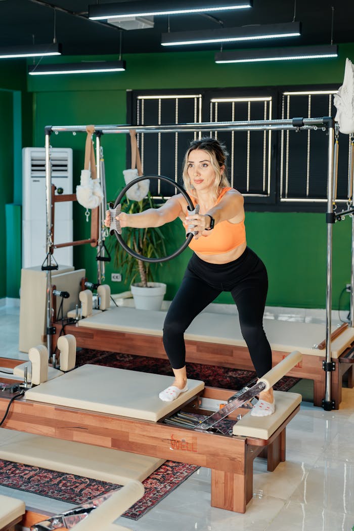 Adult woman performing pilates exercises on a reformer machine indoors. Fitness and wellness concept.